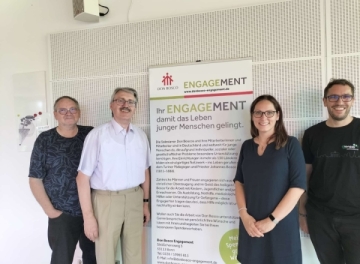 Die anwesenden Mitglieder des Grünen Netzwerks Bosco stehen um ein Transparent mit dem Titel Ihr ENGAGEMENT.