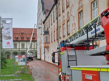 Sicherungsmaßnahmen nach dem Unwetter: Einsatzfahrzeug der Feuerwehr und Kran vor der Fassade der Basilika und des Konventbaus